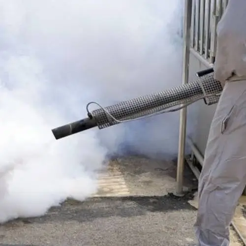 A specialist cleaner in a white suit releasing a dense cloud of smoke during the cleaning process.
