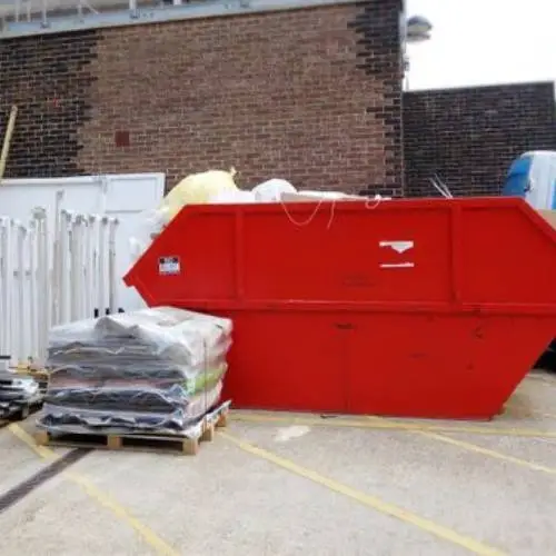 A red dumpster in front of a building, symbolizing waste collection management.